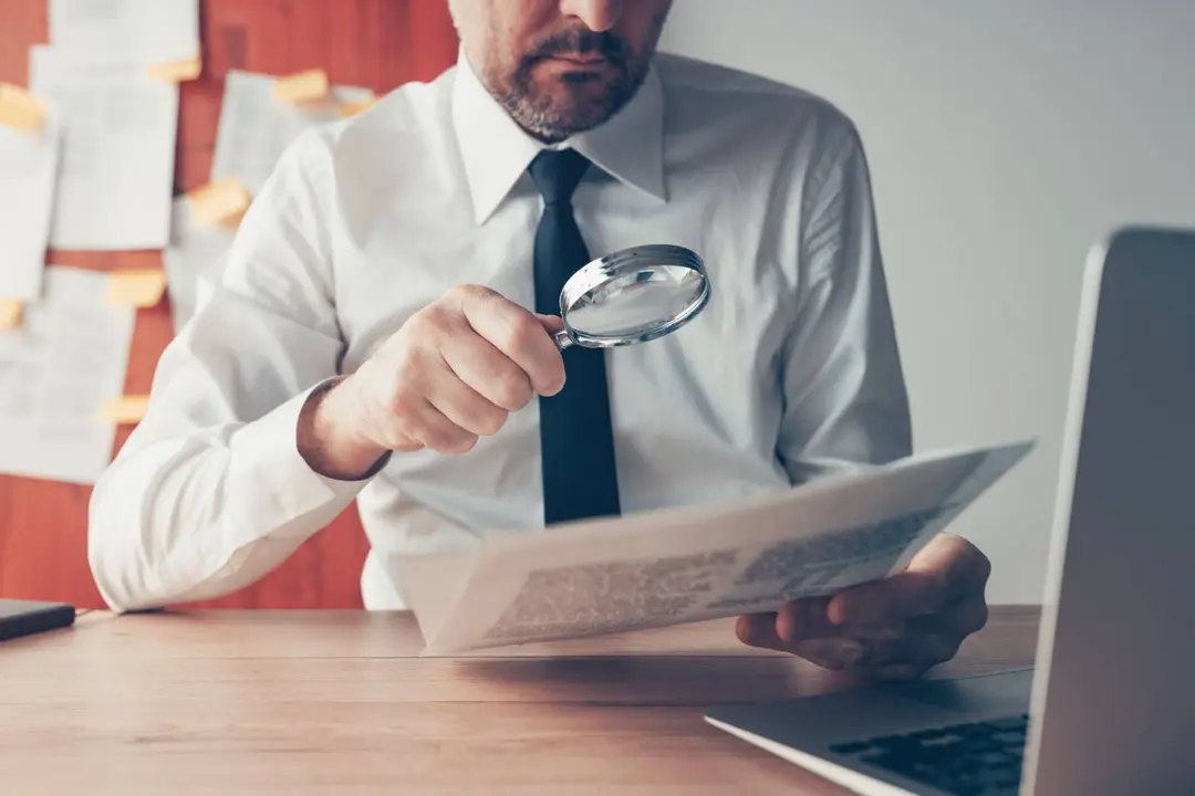 Personne examinant un document avec une loupe